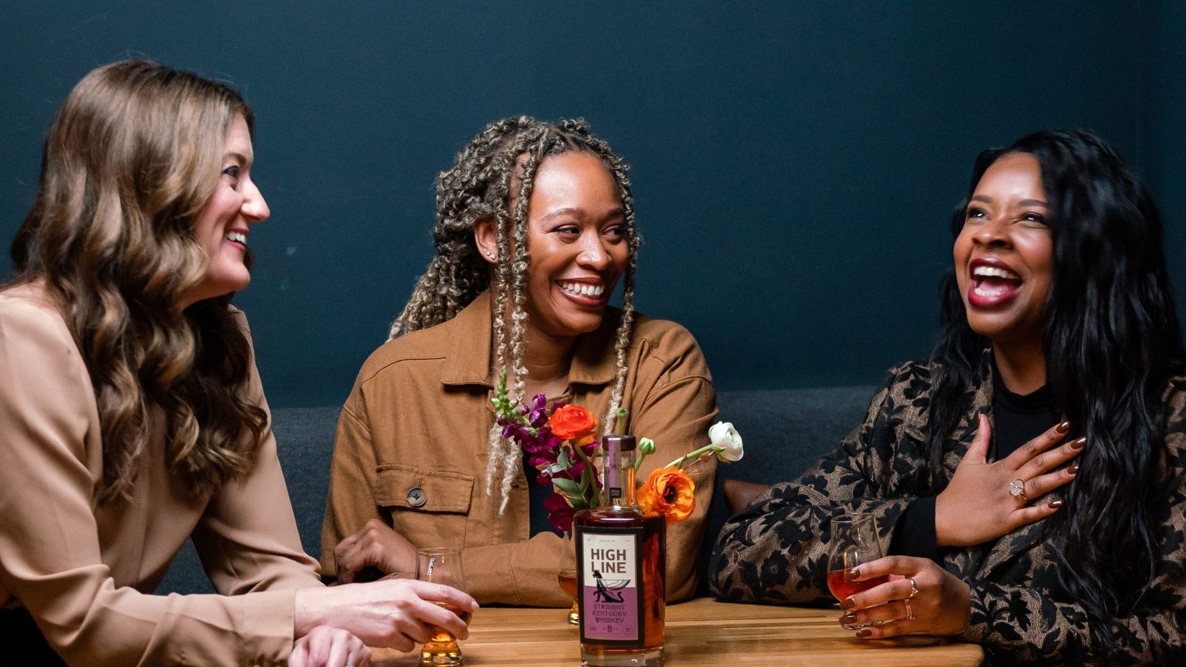 Image of three ladies sitting around a cocktail table drinking Highline Spirits.