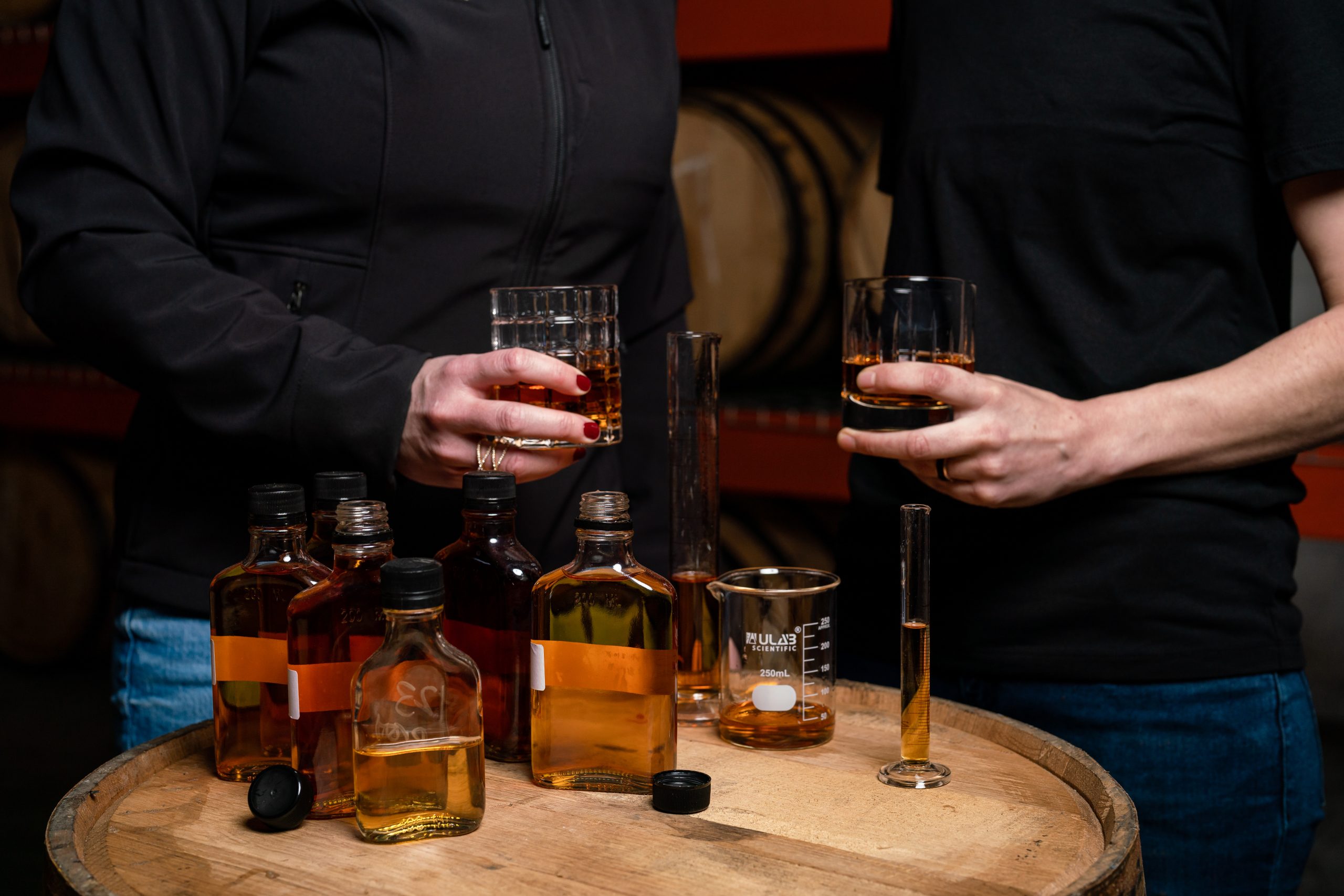 Image of two people tasting and selecting whiskeys from barrels in the Highline rick house.